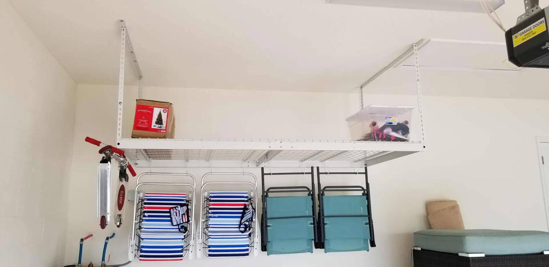 An overhead rack with two containers and four foldable chairs on its hooks