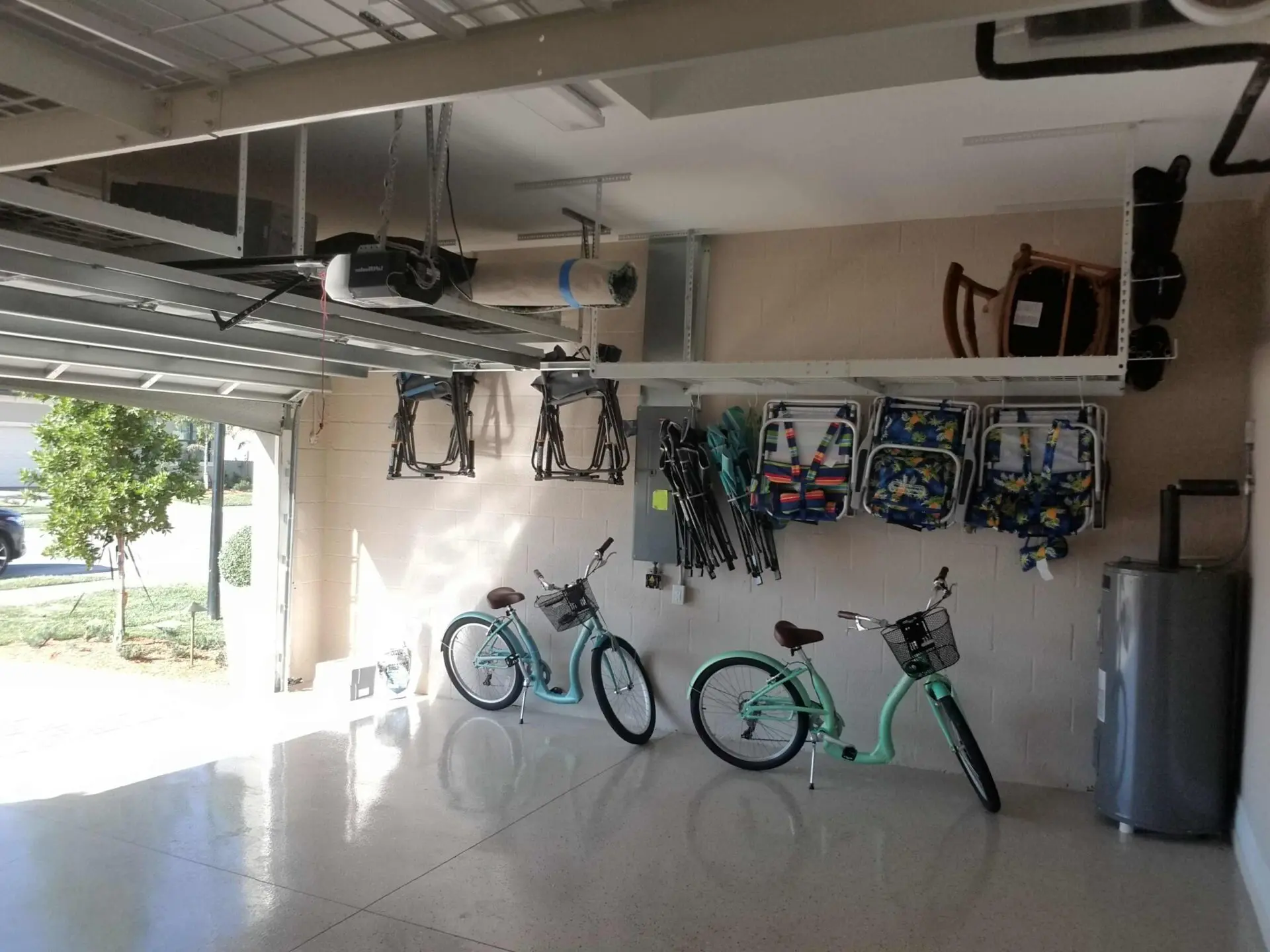 A garage with overhead storage, hooks for foldable chairs, and two bikes parked