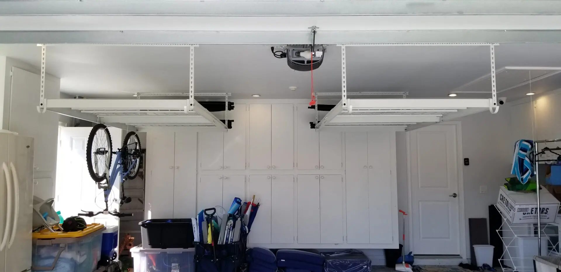 A garage with overhead storage and hooks for bicycles, cabinets at the back
